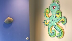 A blue door with a keyhole and a lock, a textured blue carpet, and a wall with a green octopus decoration. - The Pink Palace - Fenwick Island Beach Block w/ Pool & Super Easy Beach Access (Fenwick Island)