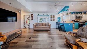 A spacious living area with a sofa, a wooden bench, and a dining table. A kitchen with a blue island and white cabinets is visible in the background. - 5 Star Comfort and Views! (Panguitch)