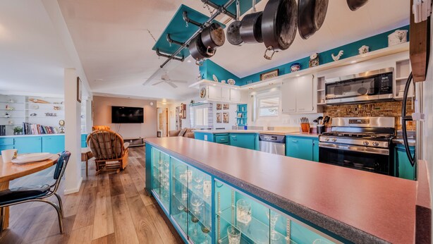 A modern kitchen with teal cabinetry, a central island, and a variety of appliances including a microwave and stove. - 5 Star Comfort and Views! (Panguitch)