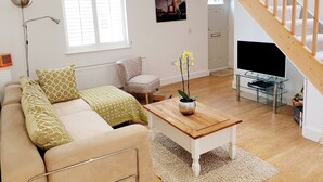 A modern living room with a sofa, a coffee table, a chair, a TV, and a staircase. - Little Eaton - Hidden Gem - Location by the sea with FREE parking  (Margate)