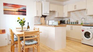 A modern kitchen with a central island, white cabinetry, and a washing machine. - Little Eaton - Hidden Gem - Location by the sea with FREE parking  (Margate)