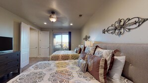 Une chambre avec deux lits, une commode, un téléviseur et un élément décoratif mural.