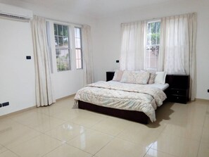 Relax in a spacious bedroom with a large bed and a nightstand with a lamp.