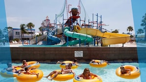A water park with multiple slides and a pool area with people on inflatable tubes.