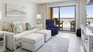 A modern living room with a white sofa, blue armchair, and a ceiling fan.