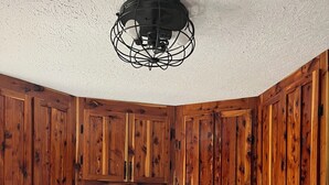 A kitchen with wooden cabinets, a white microwave, a stove, and a kettle. - Fishermen and Family’s Lakeside Nature Retreat  (Cape Fair)