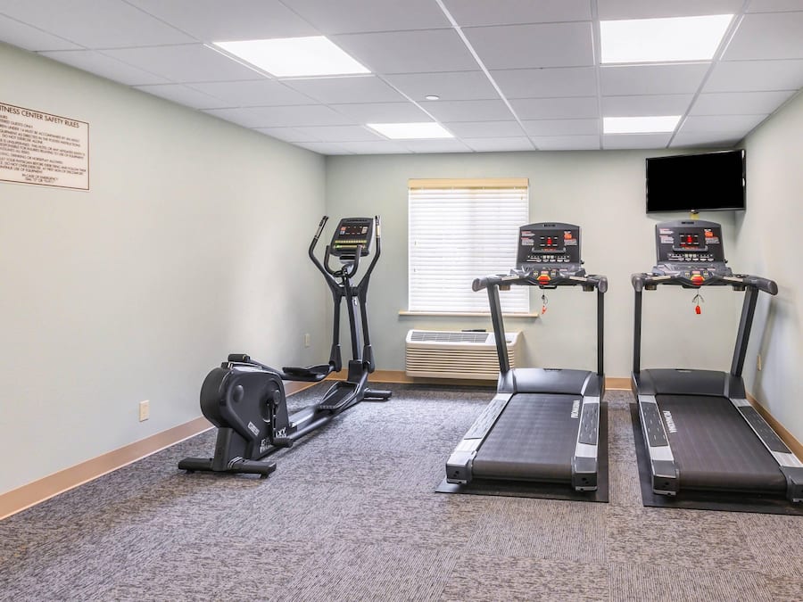 Un gimnasio con cintas de correr, elípticas y bicicletas estáticas.
