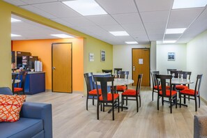 A dining area with tables and chairs, a counter with a menu, and a door. - Suburban Studios Hammond (Hammond)