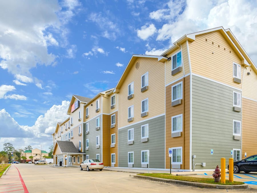 A multi-story residential building with a flat roof, multiple windows, and a parking area with a fire hydrant.