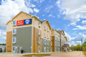 A multi-story hotel with a Suburban Extended Stay Hotel sign, multiple windows, and a parking lot. - Suburban Studios Hammond (Hammond)
