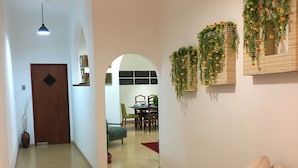 Ein modernes Wohnzimmer mit einer Couch, Holzboden, einem Essbereich im Hintergrund und Wandpflanzen zur Dekoration.