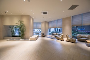 A spacious lobby with a large seating area, a water feature, and large windows. - JI Hotel (Shanghai)