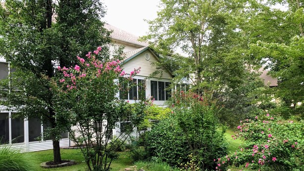 A house surrounded by lush greenery and a small pond. - Walk-In Condo With Pools in Pointe Royale - 2 Kings - Sleeps 6 (Branson)
