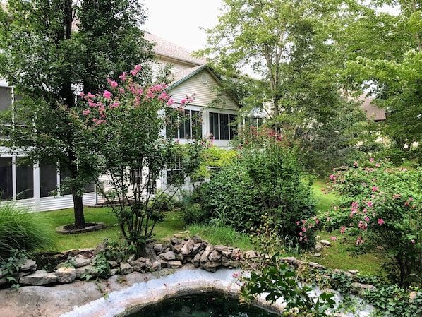 A house surrounded by lush greenery and a small pond.