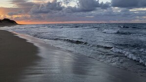 Ein Strand mit Wellen und bewölktem Himmel.
