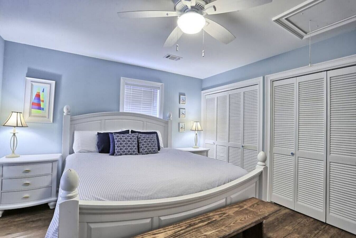 A bedroom with a bed, bedside tables, a ceiling fan, and a wardrobe.