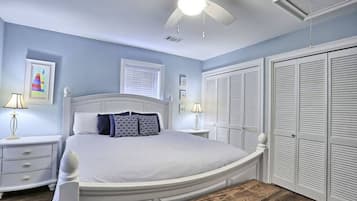 A bedroom with a bed, bedside tables, a ceiling fan, and a wardrobe.