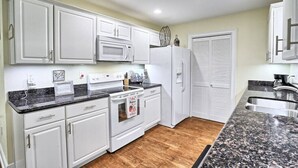 A kitchen with white cabinets, a microwave, a stove, and a refrigerator. - Pet-Friendly | Steps to Beach & Old Town BSL! (Bay St. Louis)