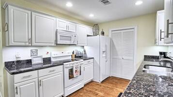 A kitchen with white cabinets, a microwave, a stove, and a refrigerator.