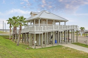 A waterfront house with a balcony, a covered porch, and a view of the ocean.