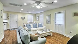 A living room with a sectional sofa, a coffee table, and a ceiling fan. - Pet-Friendly | Steps to Beach & Old Town BSL! (Bay St. Louis)