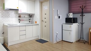 Eine kleine Küche mit weißen Schränken, einer Mikrowelle und einem Kühlschrank.