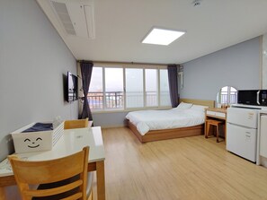 Ein Hotelzimmer mit Bett, Schreibtisch, Stuhl, Mikrowelle und kleinem Kühlschrank.