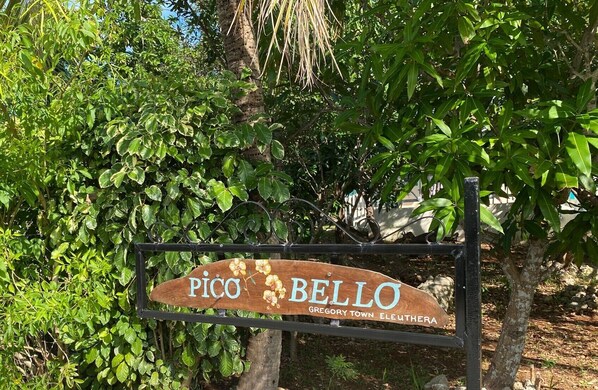 Un letrero de madera con la inscripción 'PICO BELLO' y 'Gregory Town Eleuthera' que indica una ubicación.
