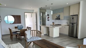 A modern kitchen with a central island, wooden cabinets, and stainless steel appliances.