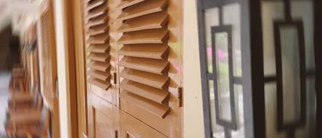A corridor with wooden doors and windows with shutters.