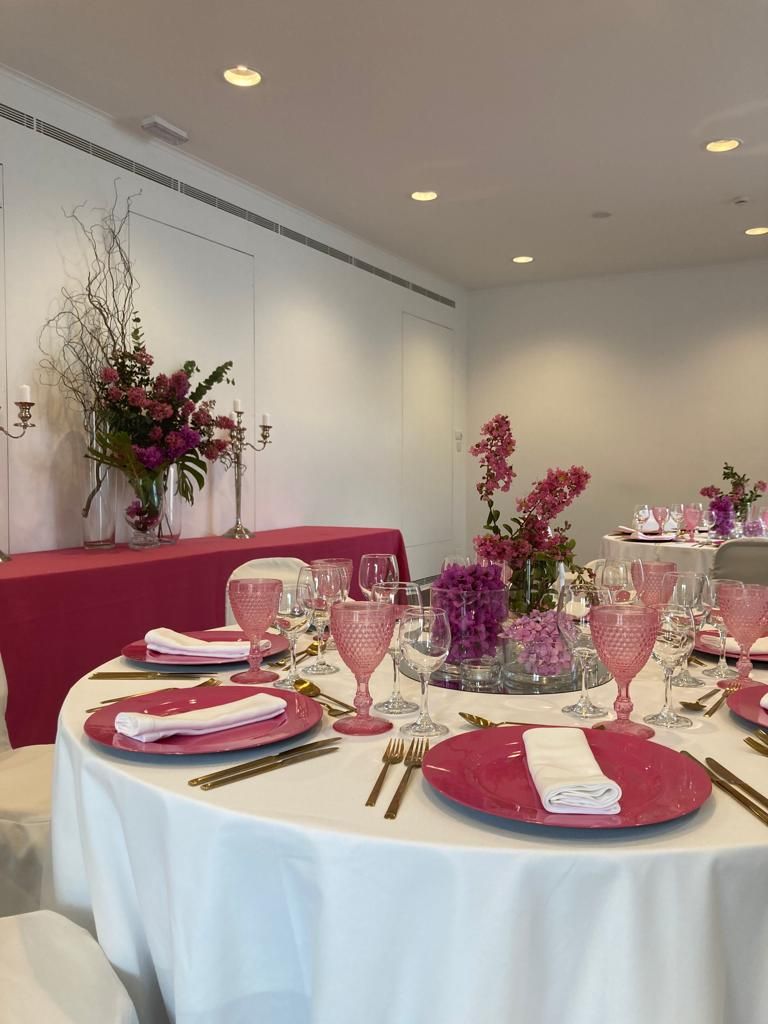 Un tavolo rotondo apparecchiato per un pasto, con tovaglioli rosa, bicchieri e posate.