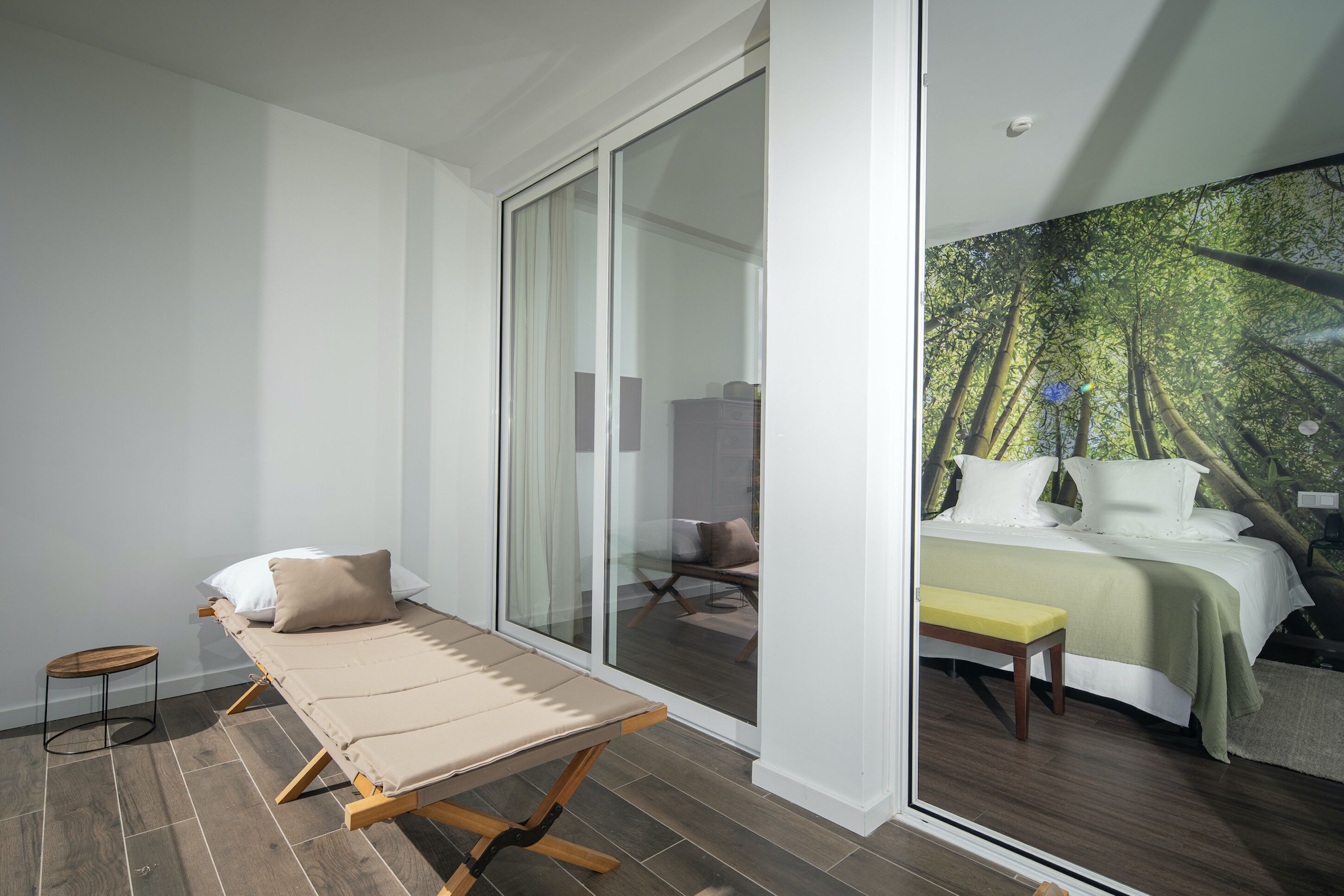 Une chambre à coucher comprenant un lit, un banc et une porte-fenêtre coulissante donnant sur une salle de bain.