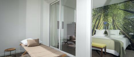 Quarto com cama, um banquinho e uma porta de correr para um banheiro.