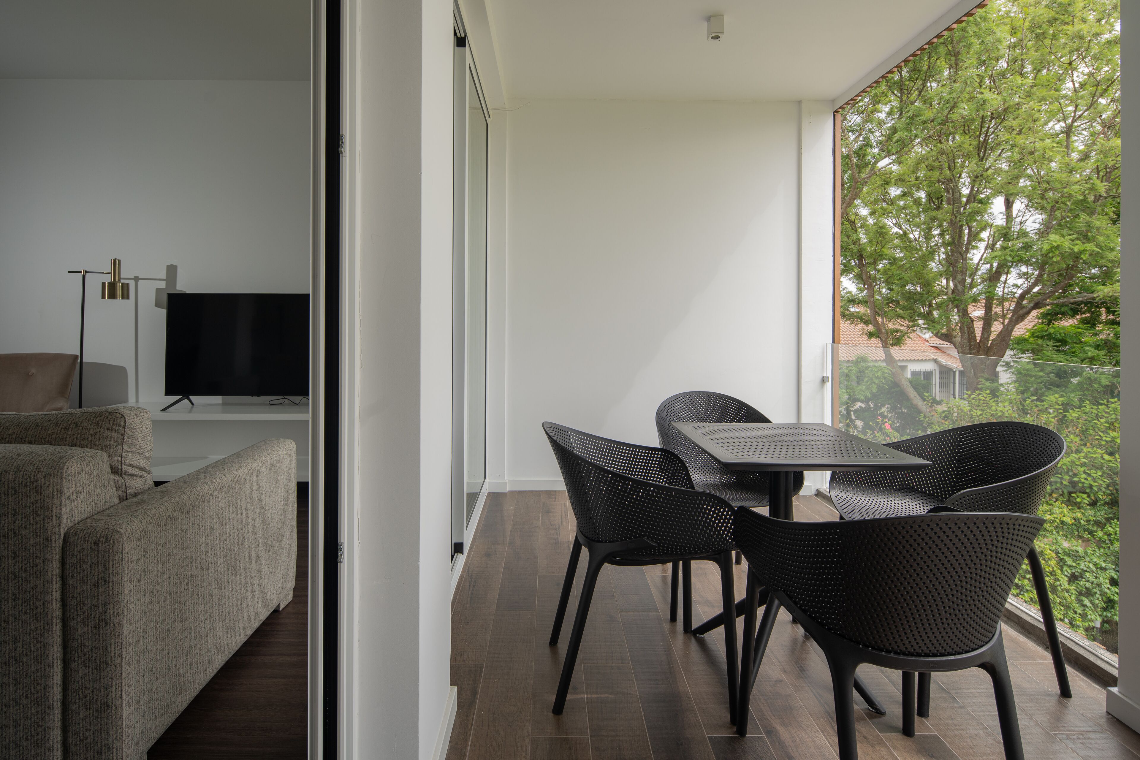 Een moderne woonkamer met een bank, een televisie en een eethoek met stoelen en een tafel.