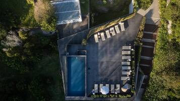Vista aérea de una azotea con piscina, tumbonas y un panel solar.