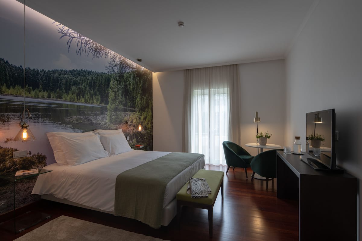 A modern bedroom with a large bed, a desk, and a chair.