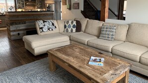 Un salon moderne avec un canapé d’angle, une table basse en bois et un tapis à motifs.