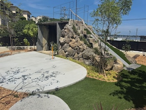 Un área ajardinada con un sendero de hormigón, césped verde y una estructura de piedra.