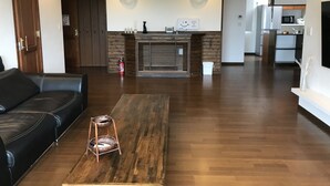 A modern living room with a black leather sofa, a wooden coffee table, and a fireplace with a mantel.