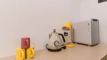 A desk with a kettle, two mugs, a lamp, and a speaker.