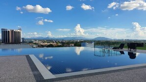 A rooftop infinity pool with clear views of mountains and a cityscape. - Regatta Stay Kozi Square Kuching (Kuching)