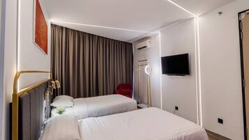 Een hotelkamer met twee bedden, een flatscreen televisie, een airconditioning en een rode stoel.