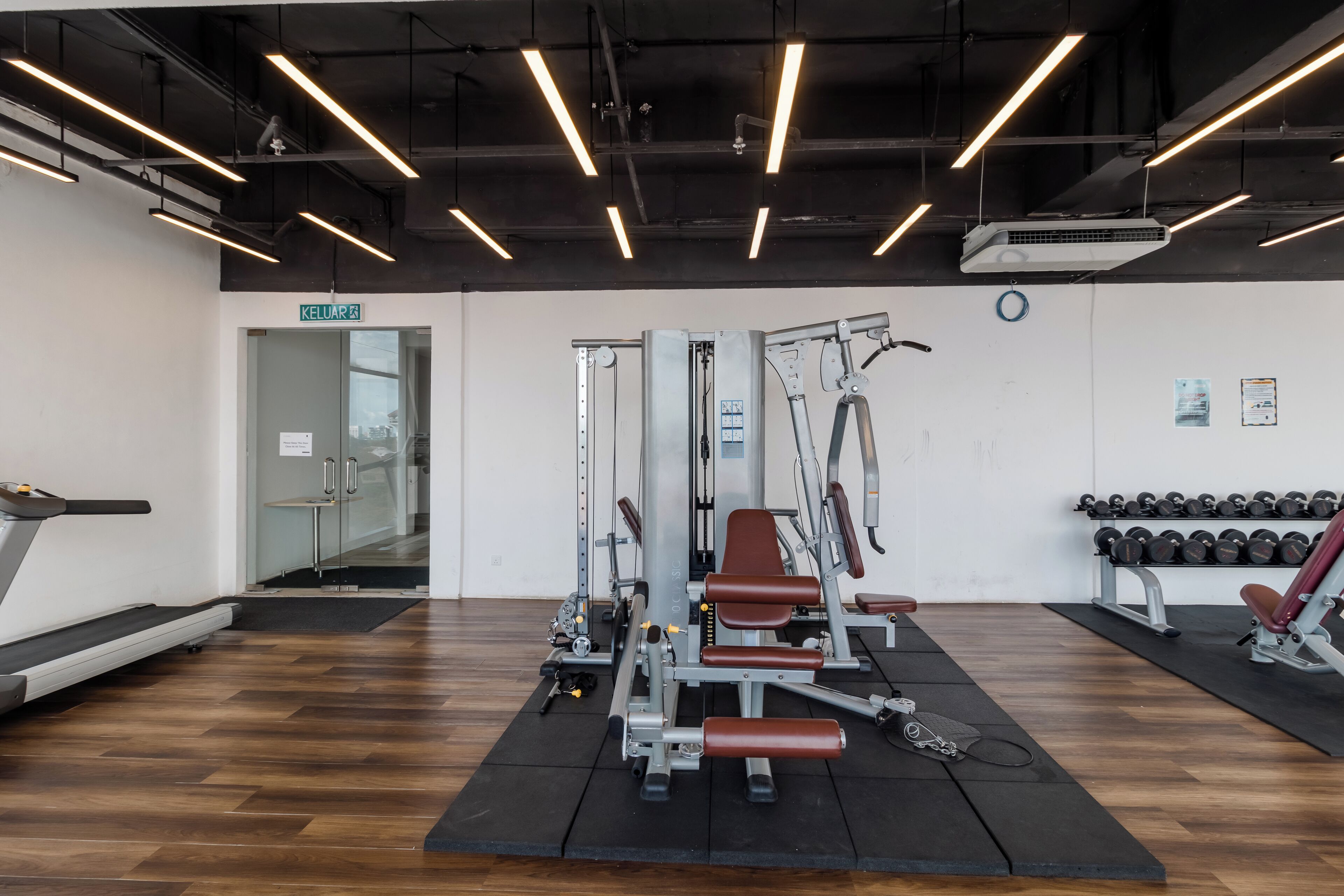 A gym with a treadmill, weight machines, and dumbbells.