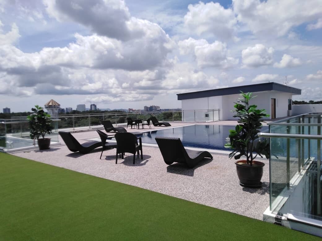 Una terraza en la azotea con piscina, sillas de descanso y plantas en macetas.