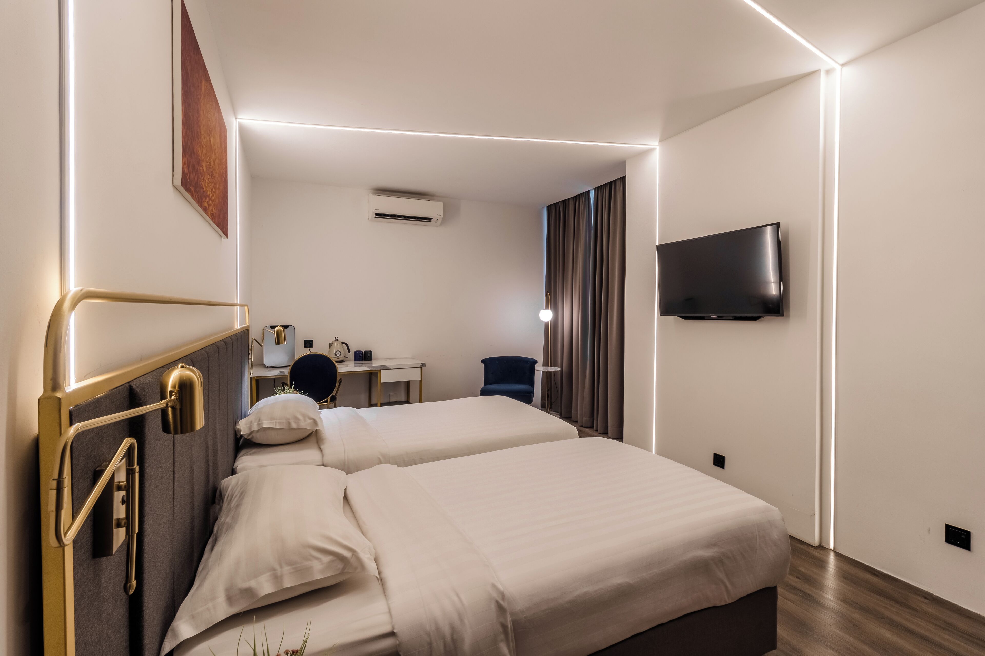 Une chambre d’hôtel avec deux lits, un bureau, une chaise, une télévision et un appareil de climatisation.