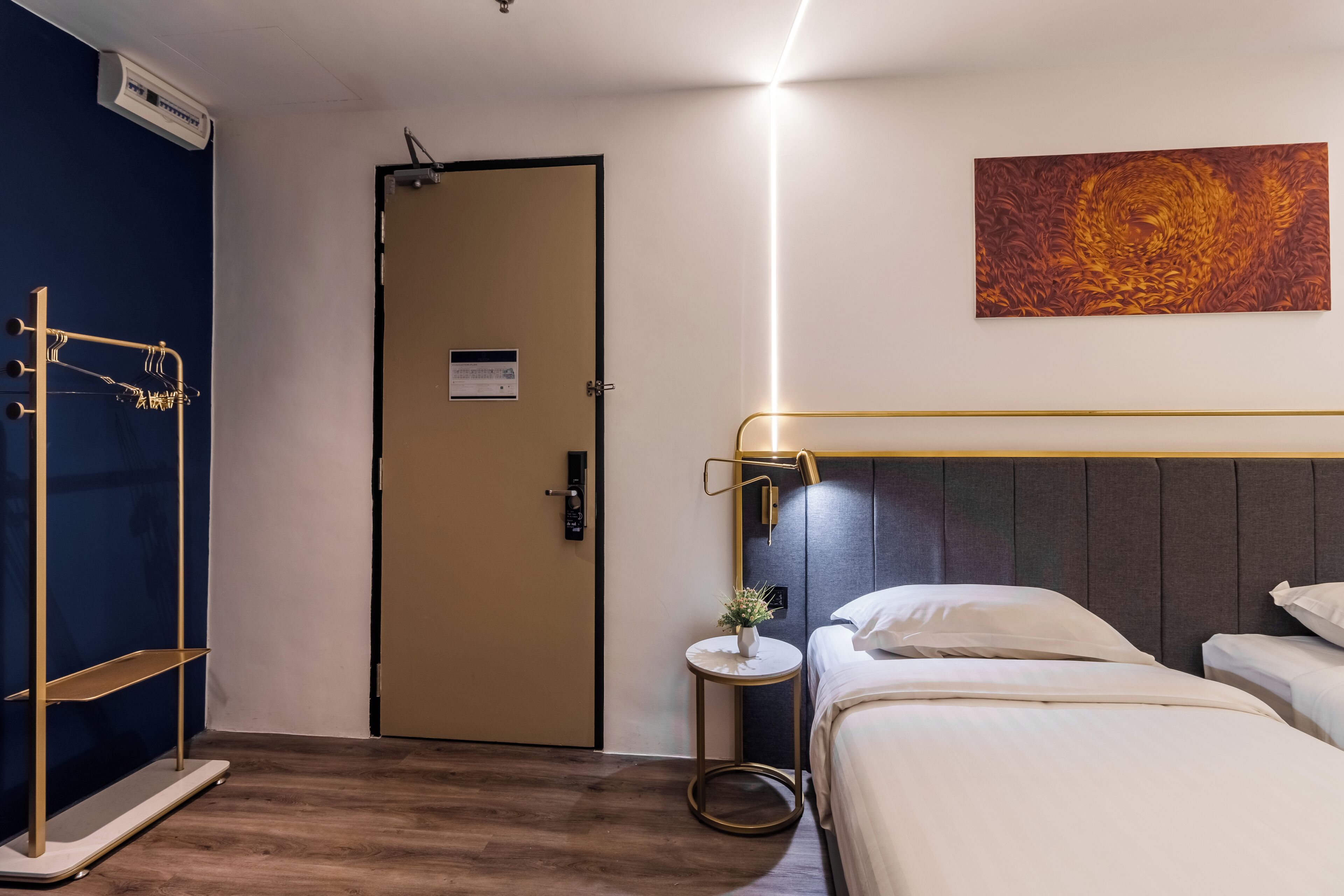 A hotel room with a bed, bedside table, and a wall-mounted artwork.