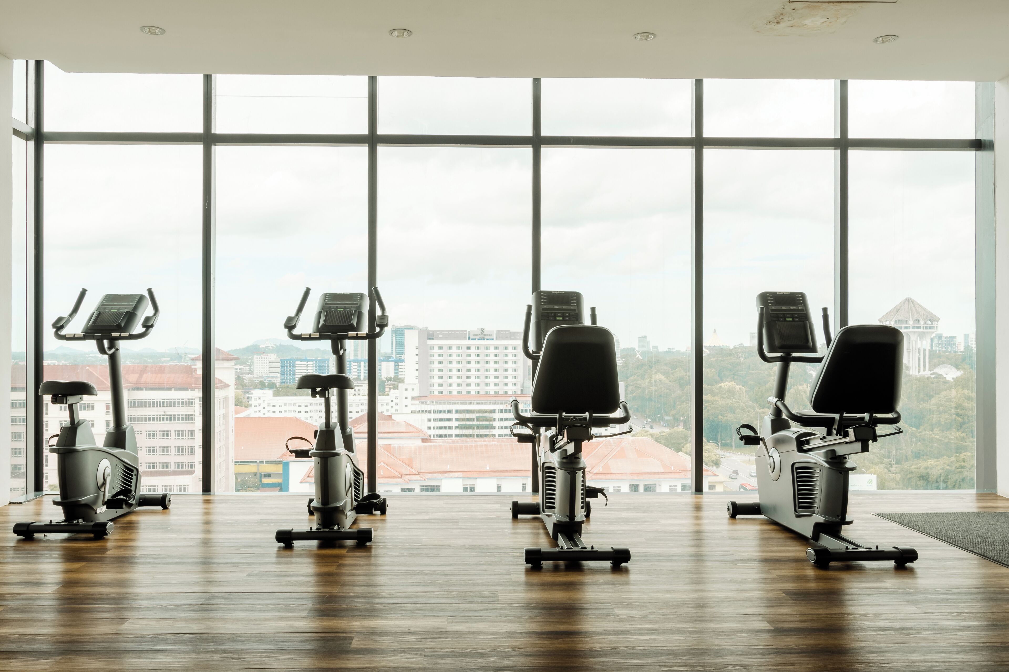 A gym with exercise equipment and large windows offering a city view.