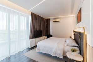 A modern hotel room with a large bed, a bedside table, a TV, and a view of the outdoors. - Regatta Stay Kozi Square Kuching (Kuching)