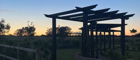 A pergola structure in a rural setting with a clear sky.