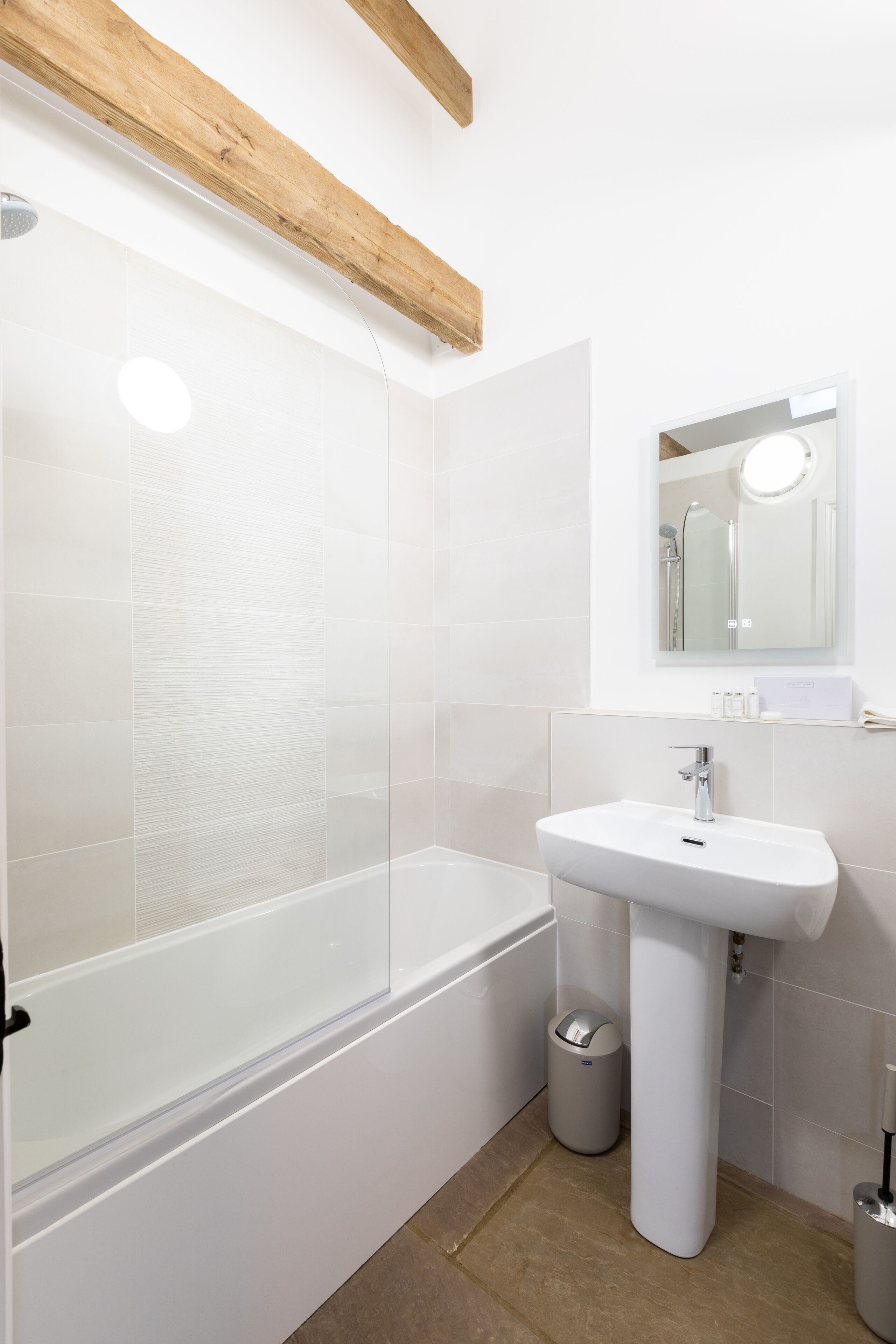 A modern bathroom with a glass-enclosed shower, a white sink, and a mirror above it.